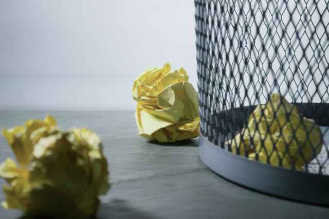 focus photo of yellow paper near trash can